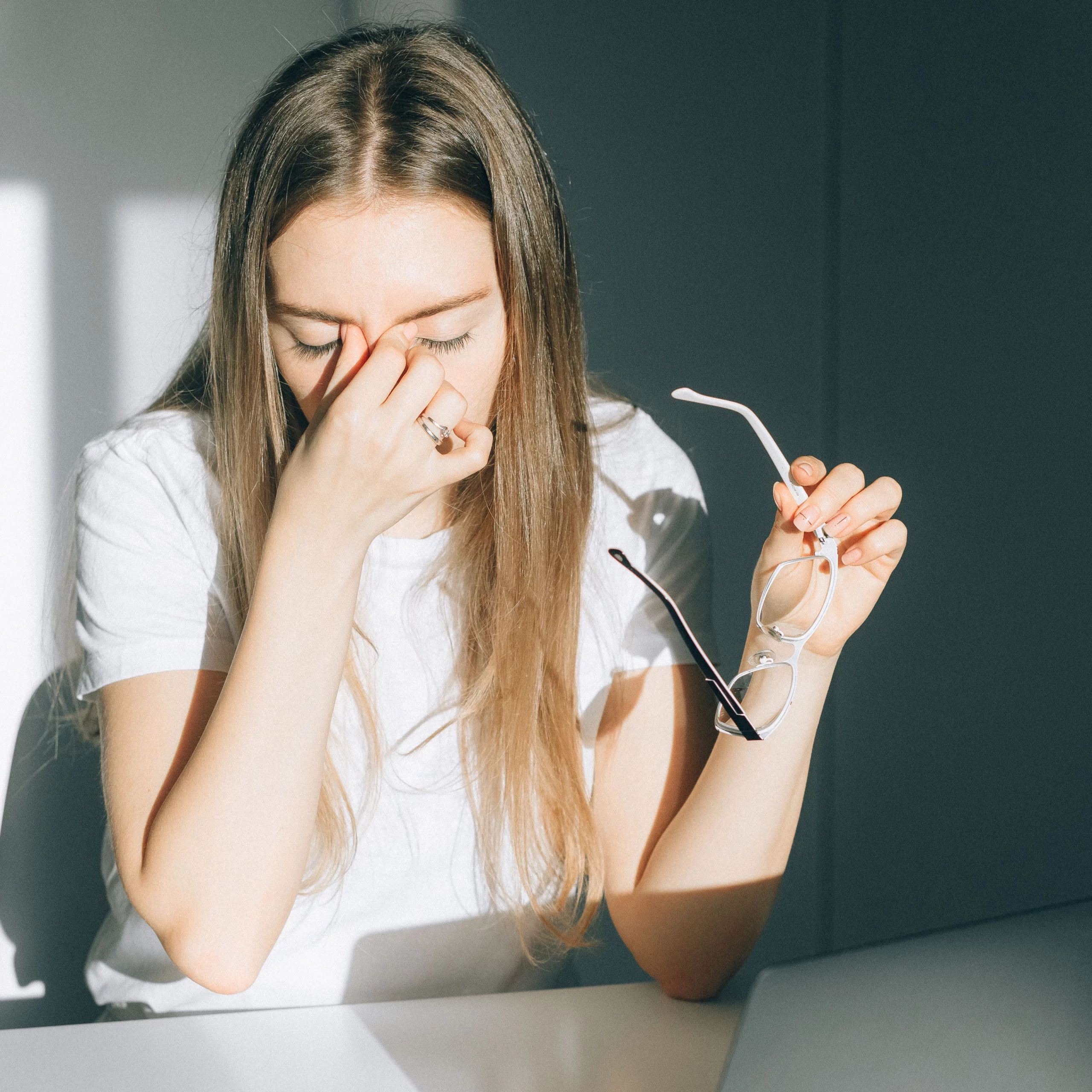 Femme épuisée retirant ses lunettes devant son ordinateur en journée copie